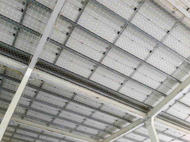 Large parking lot or basketball court with large solar panels that generate clean, renewable energy, looking down from below, protected by a protective net on the bottom of the solar panels