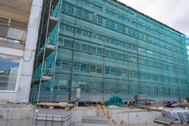 Building under construction wrapped green protection safety net.